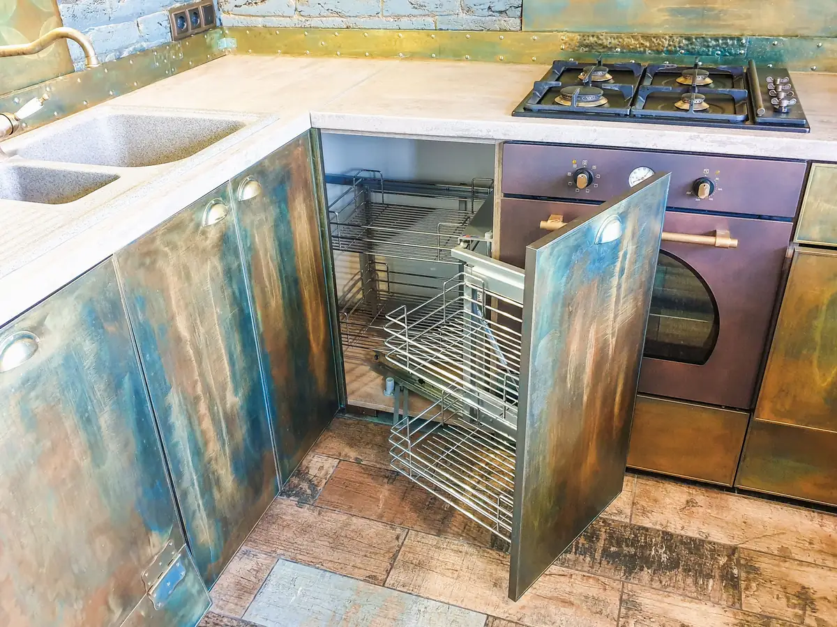 A corner cabinet with pull-out wire baskets swung out on runners