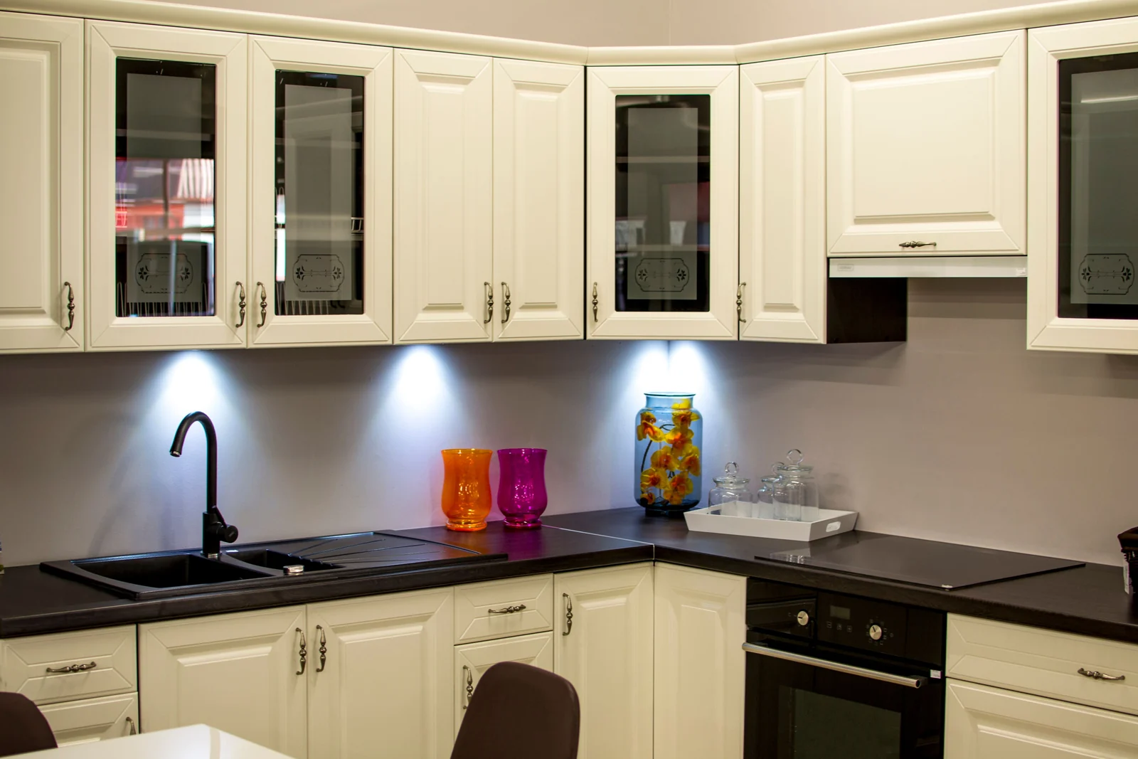 Cream raised-panel cabinets with glass doors and under-cabinet lighting