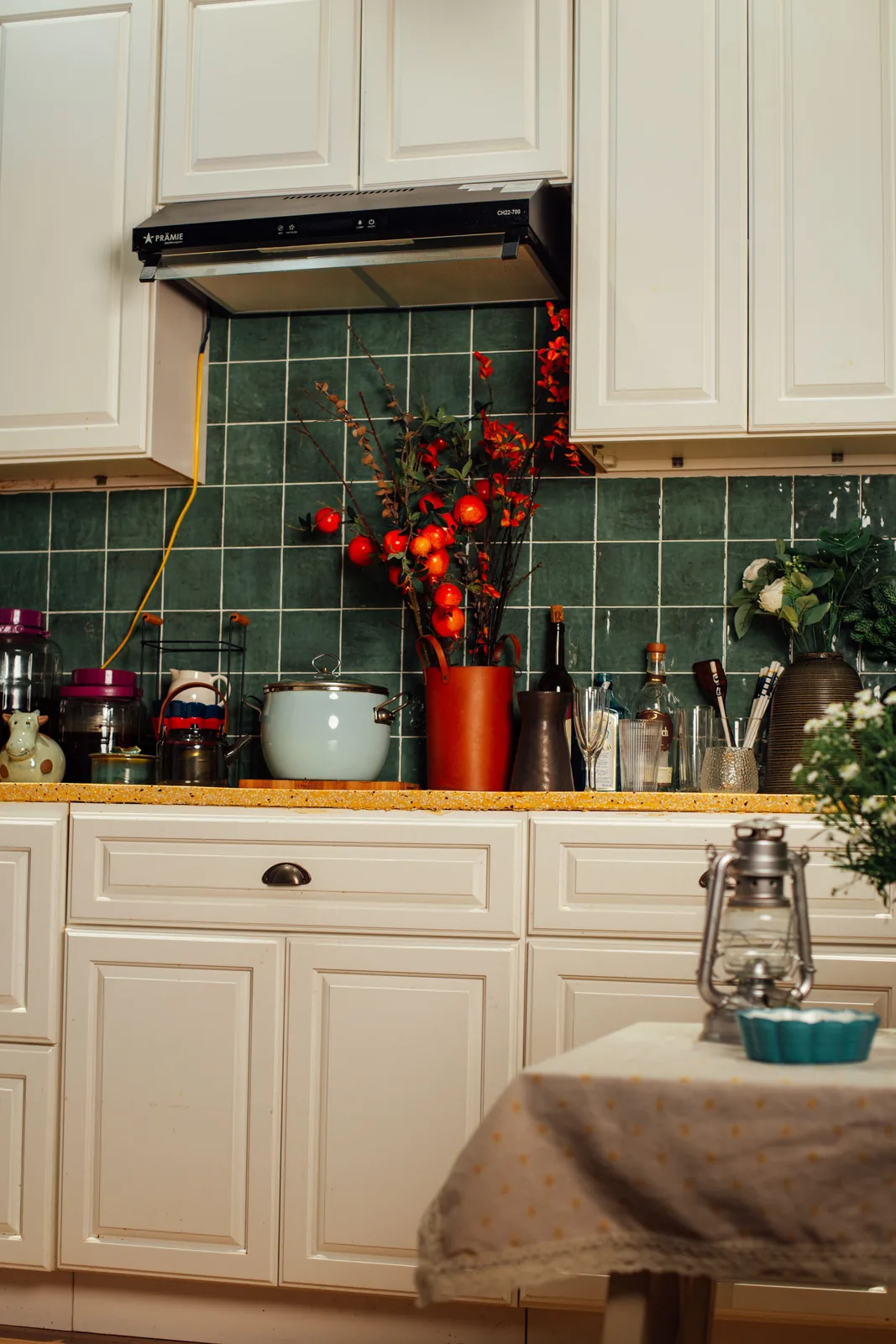 Cream raised-panel doors above green tile and a terrazzo worktop