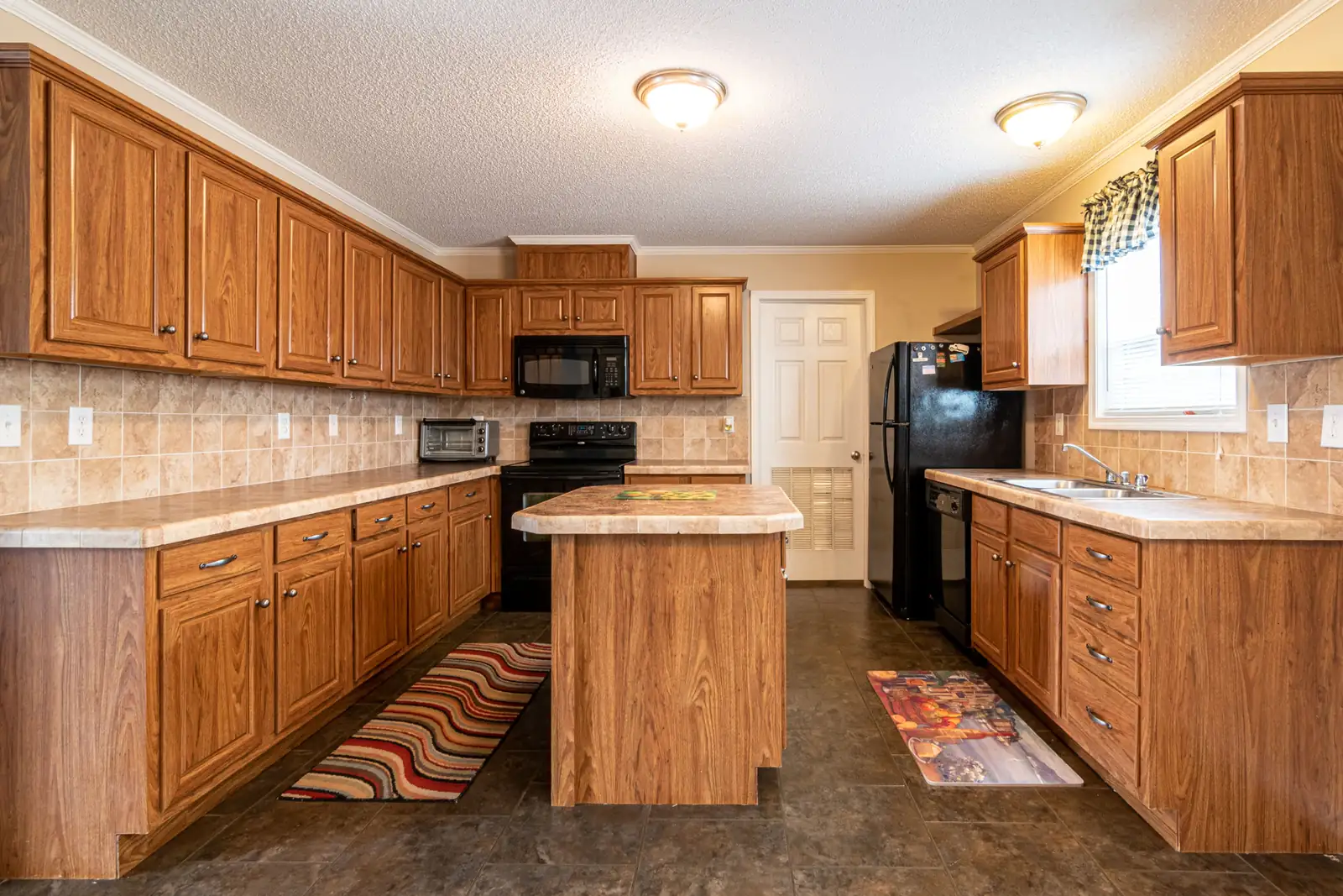 A golden oak raised-panel kitchen with a tiled worktop