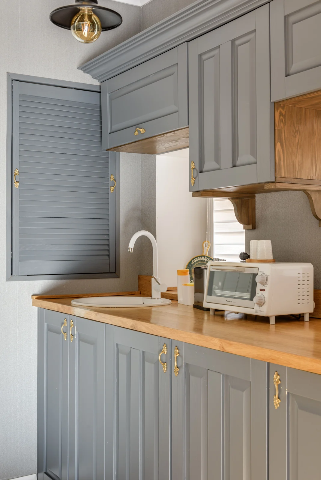 Grey painted cabinet doors with brass handles and a wood worktop