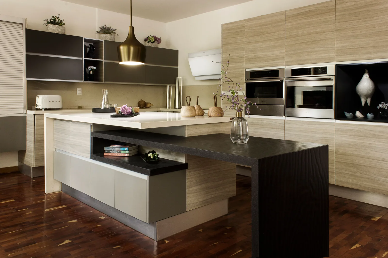 A light wood kitchen with a two-level island and stone top
