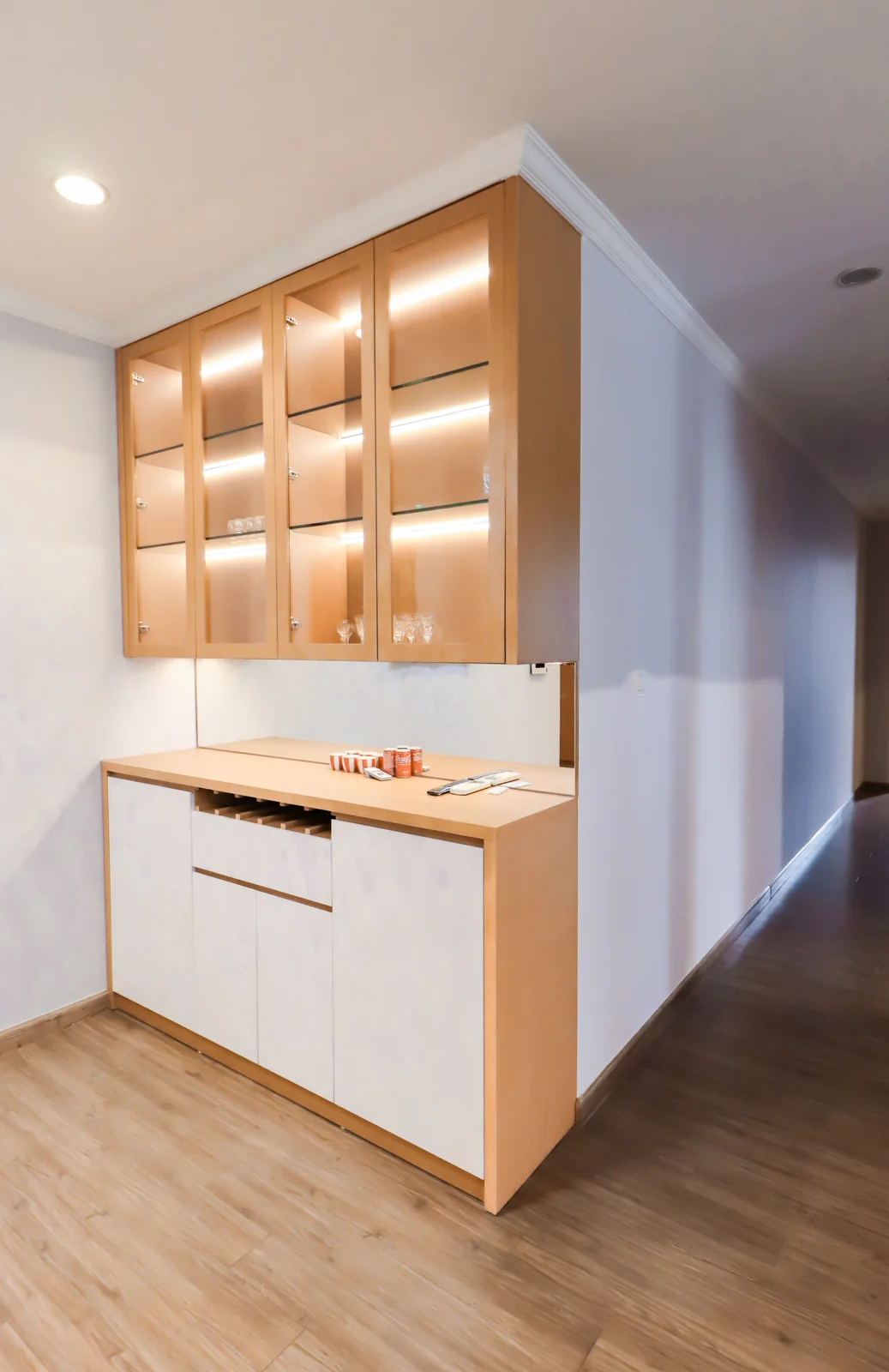A maple display cabinet with lit glass shelves over a white base