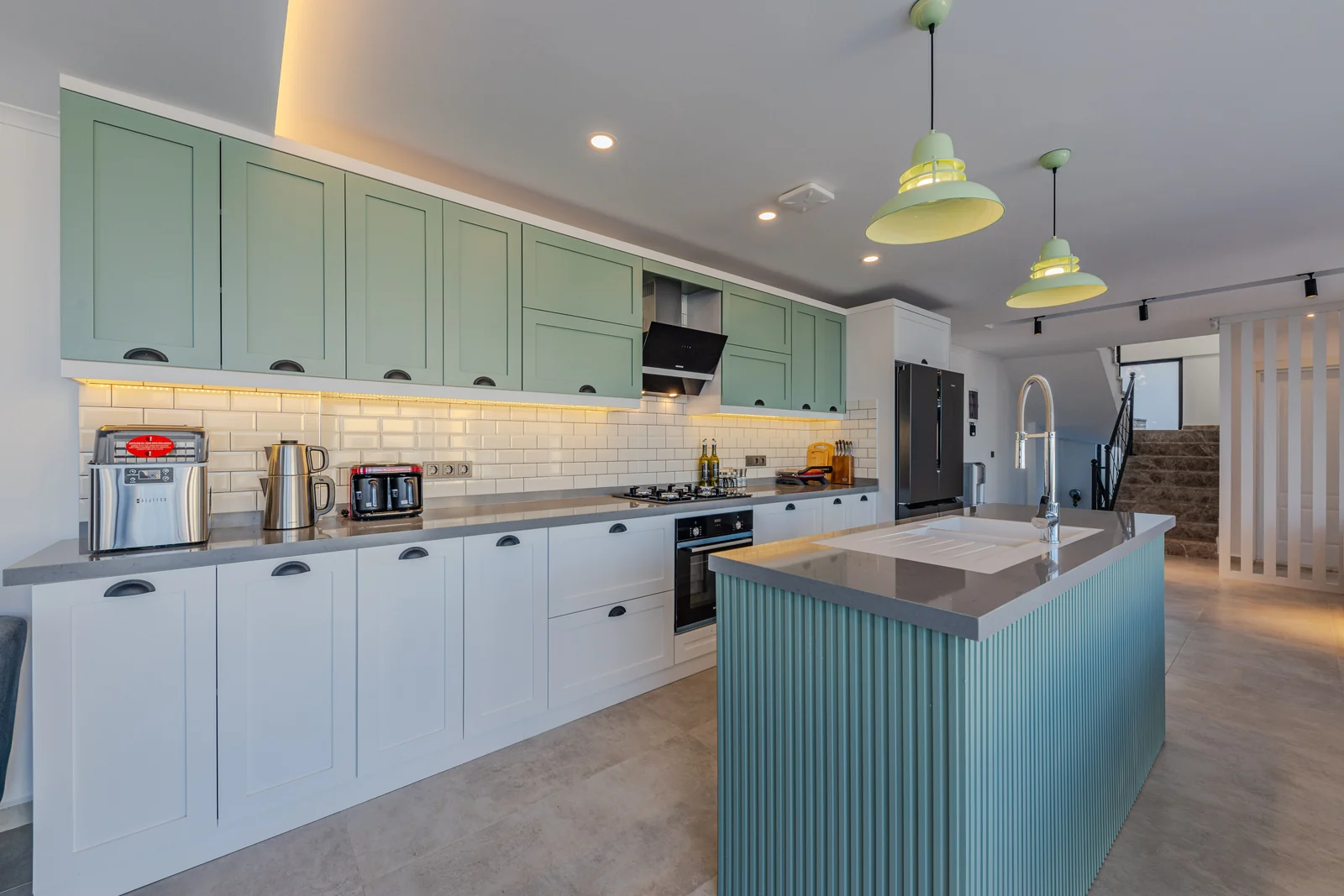 Sage green shaker uppers with white bases and a fluted island