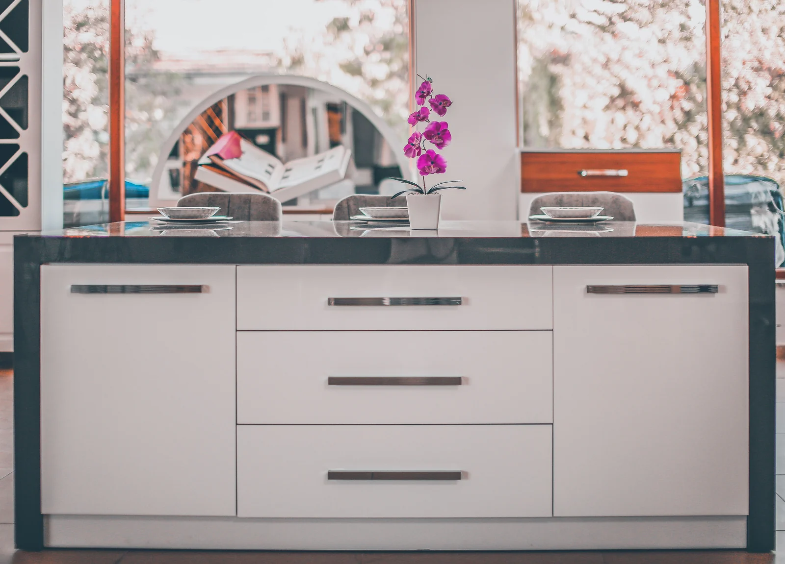 A white gloss island with a dark worktop and long bar handles