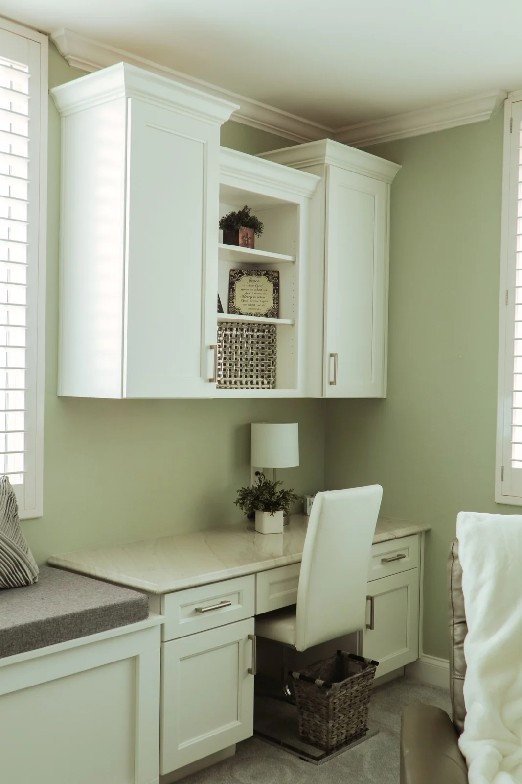 A built-in white shaker desk and window seat with a stone top