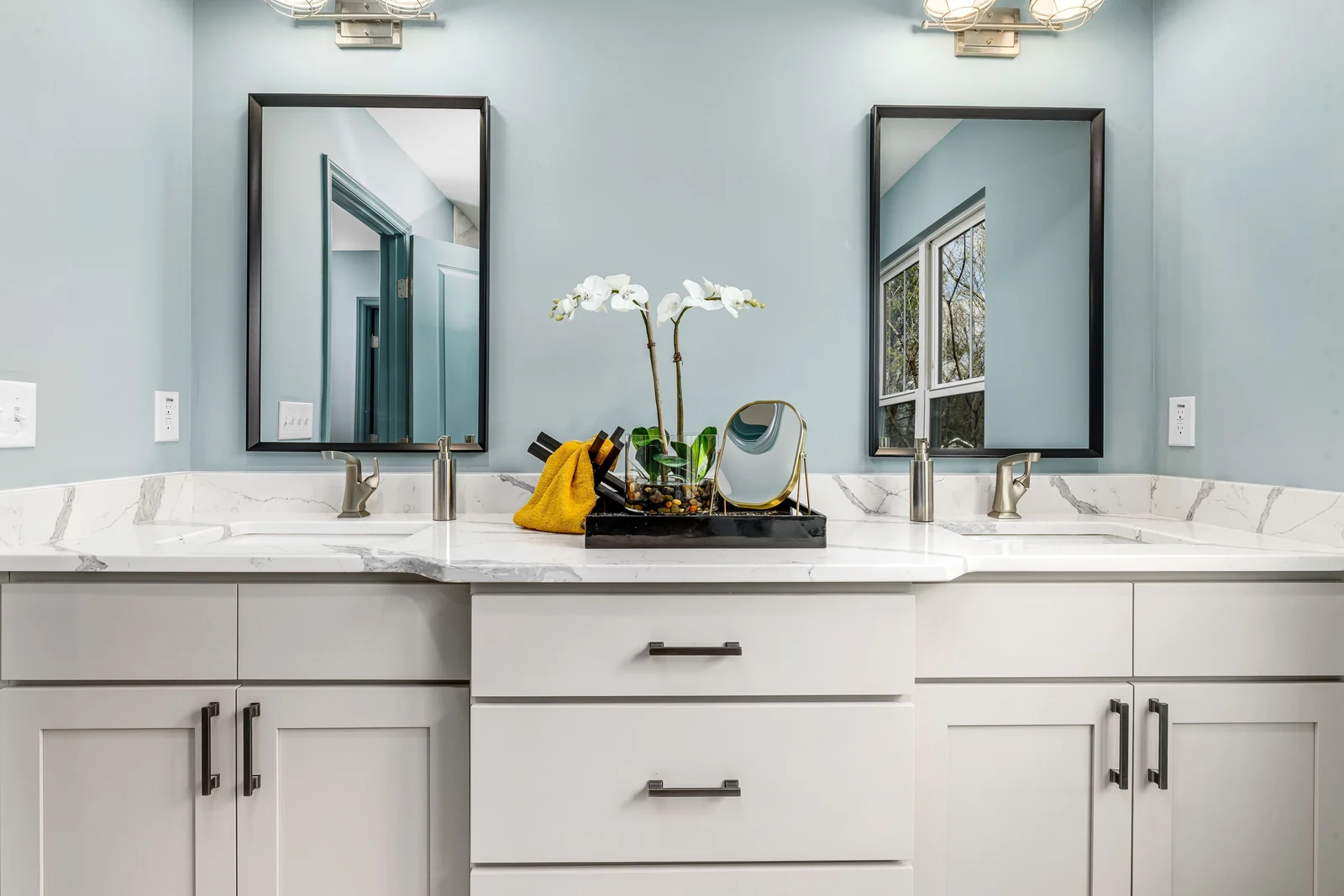A white shaker double vanity with a marble top and twin mirrors